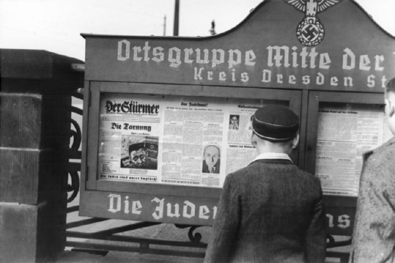 German boys read an issue of the Stuermer newspaper that is posted in a display box at the entrance to a Nazi party headquarters